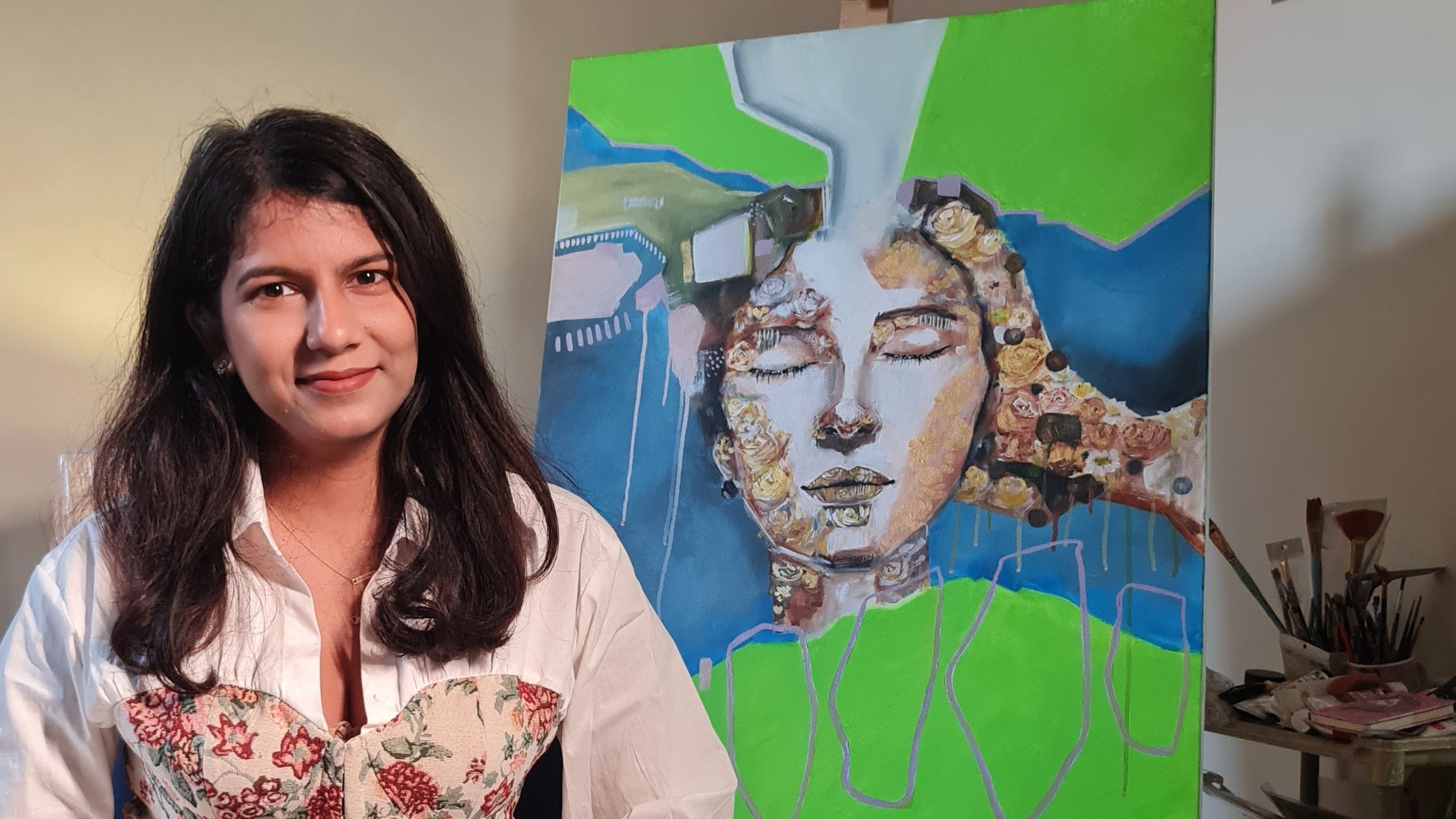 Monisha Tripathy aka Nikkie sitting on a couch with a colorful painting of a woman called connected in the background